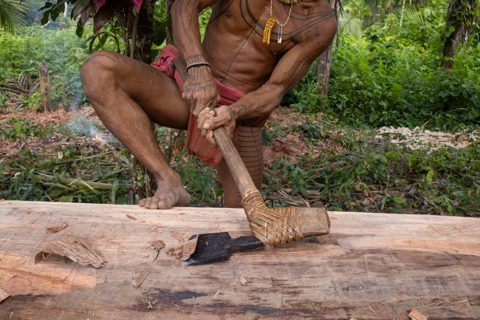 Mentawai shaman making dugout canoe