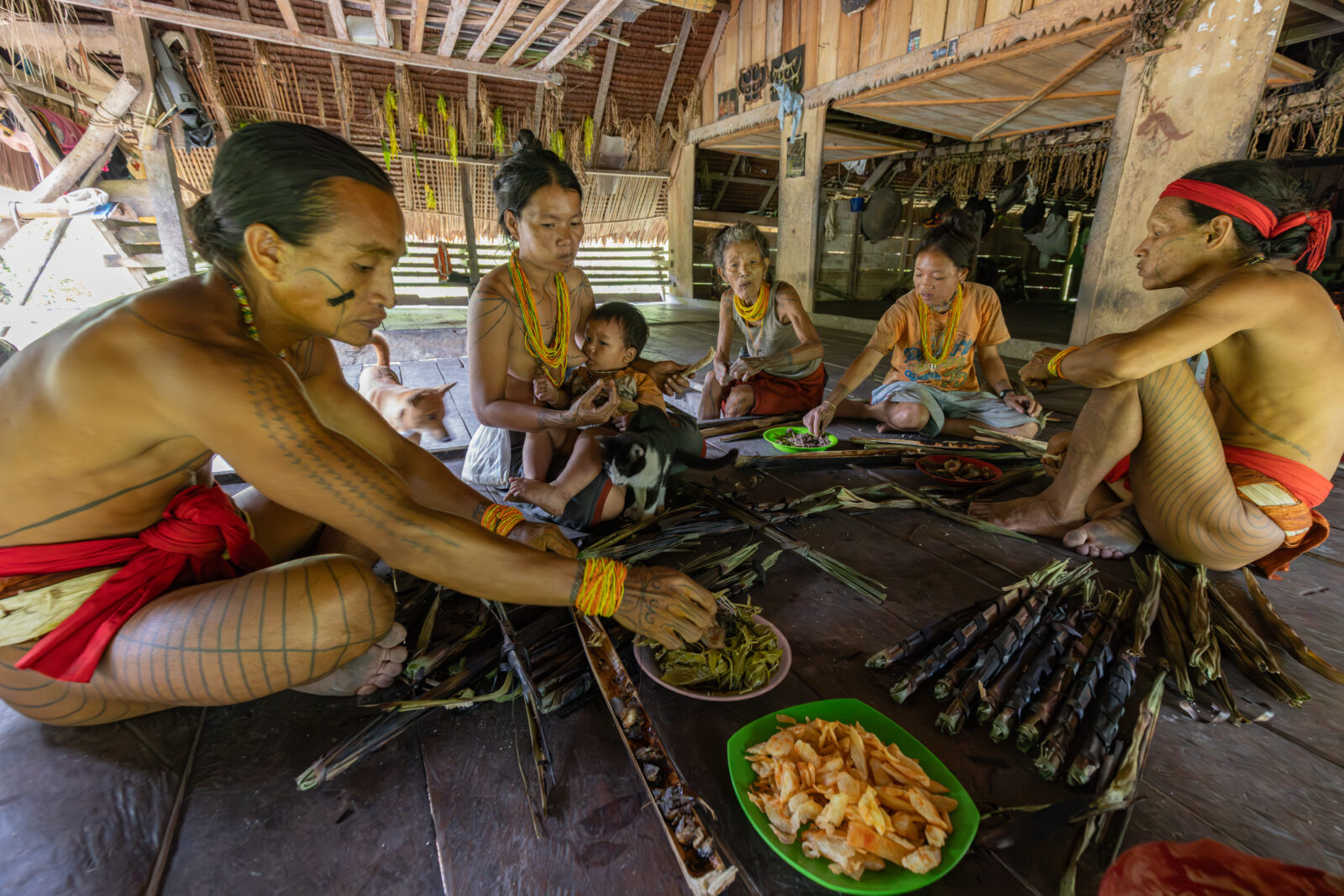 Mentawai family eating a meal in traditional uma longhouse