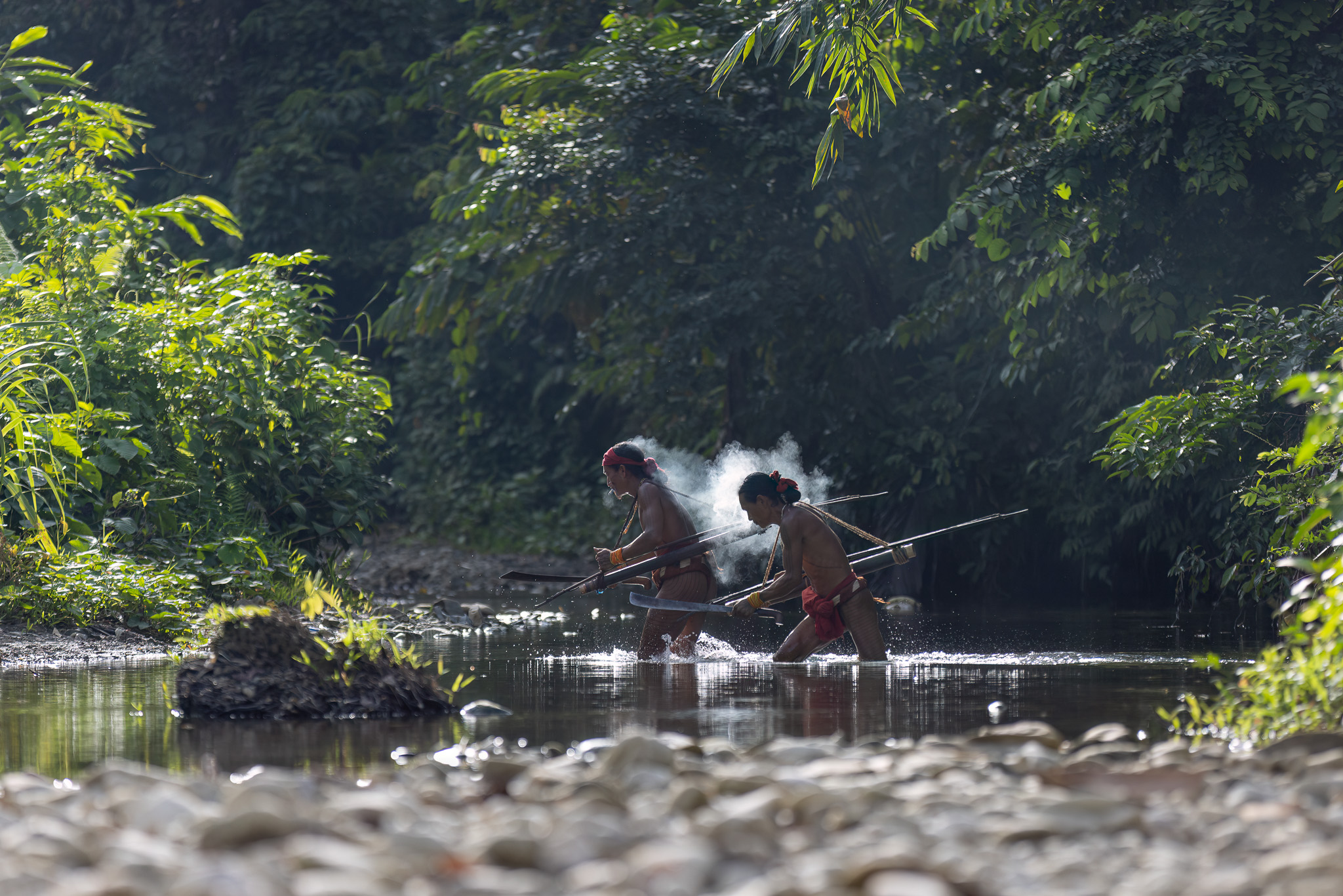 Mentawai shamans crossing river on Siberut Island Indonesia