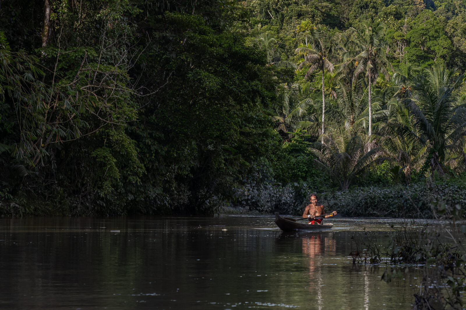 mentawai shaman in canoe on river