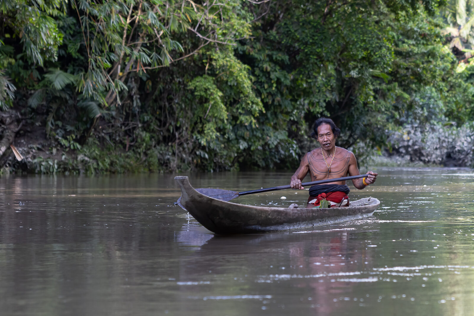 A Mentawai shaman paddling with his canoe through the Siberut Island rainforest