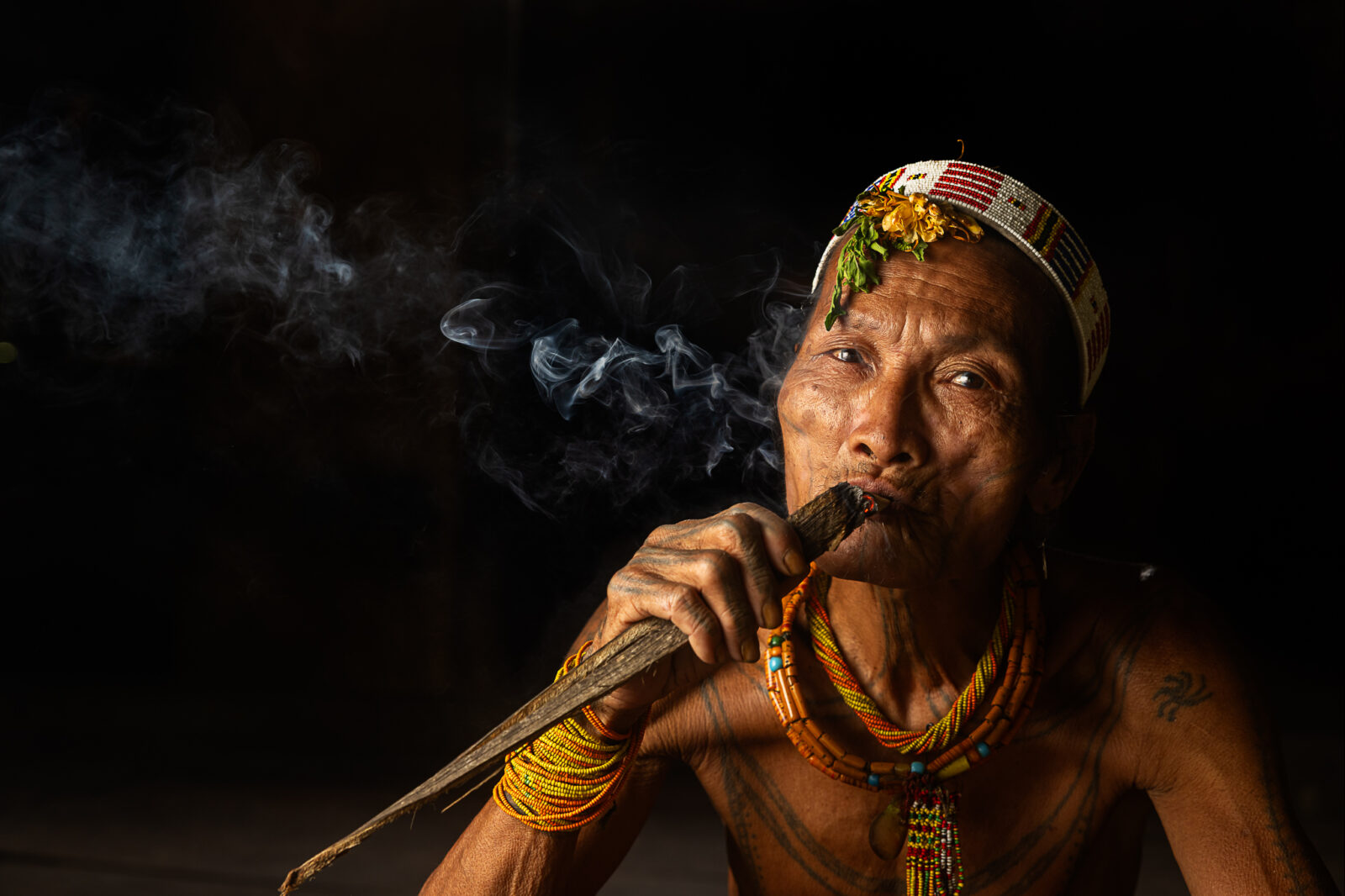 Mentawai shaman smoking traditional tobacco cigarette.